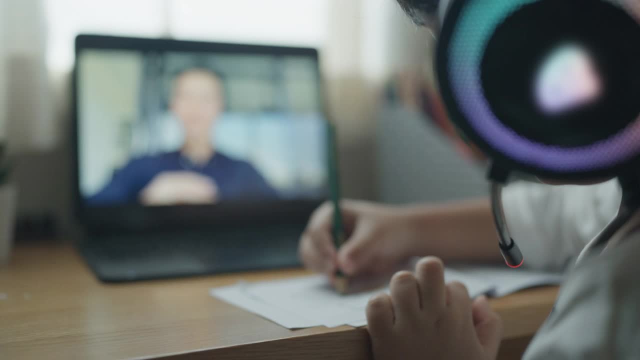 一个戴着耳机在家学习的男孩视频素材