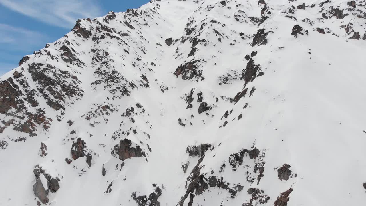 山上覆盖着积雪的岩石山坡。用于极限滑雪的陡峭的峡谷。高级骑手免费搭乘。鸟瞰图视频素材