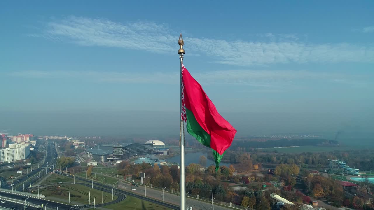 晴朗的早晨，白俄罗斯国旗飘扬在蔚蓝的天空和明斯克的城市景观上视频素材