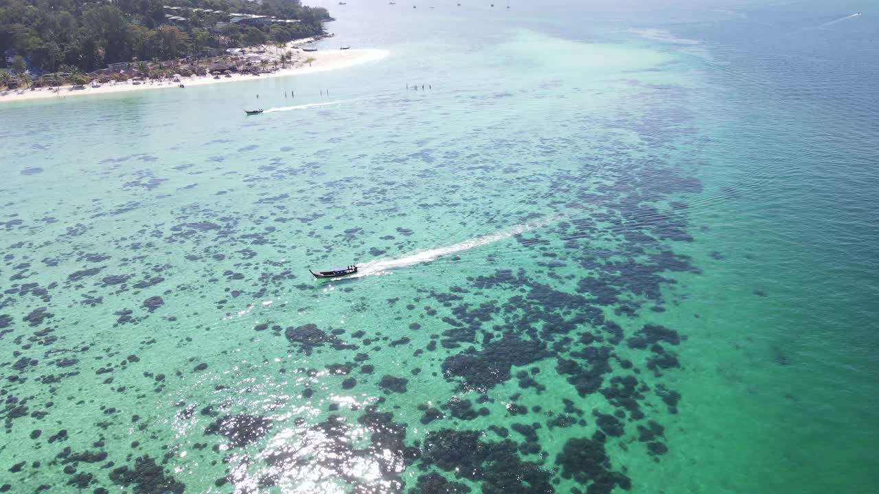 在泰国南部的Koh Lipe岛，无人机拍摄了一艘游船在海中的珊瑚上航行的高空高角度，俯视图视频素材