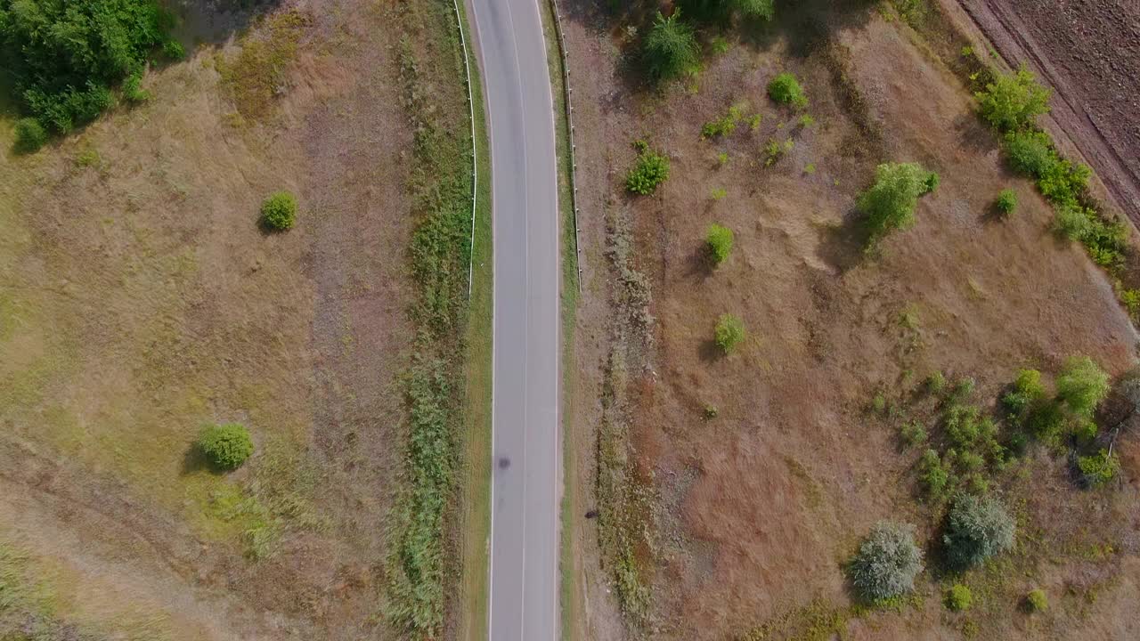 无人机正飞过一条柏油乡村公路。汽车在高速公路上行驶。田地之间的乡村公路。4 k, ProRes视频素材