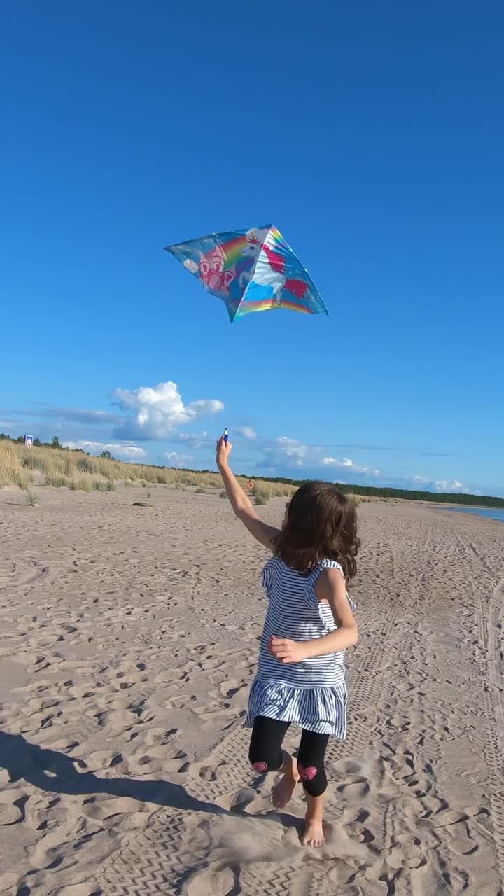 小女孩玩着五颜六色的风筝在美丽的北海滩上奔跑视频素材