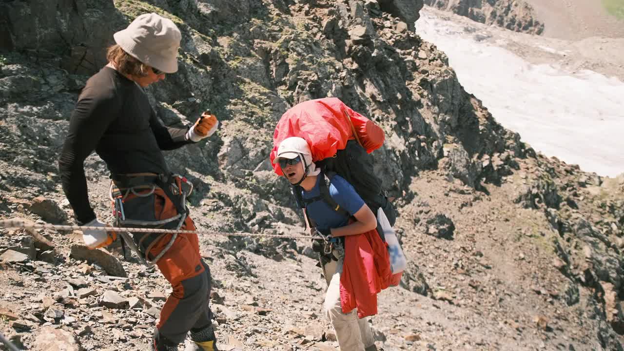 登山者在确保系统和绳索的帮助下，沿着山路艰难的一段走下去。视频素材