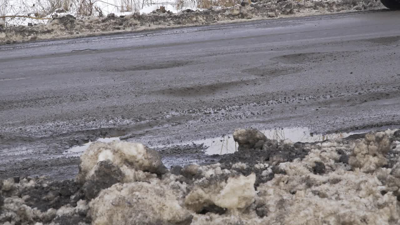 冬季道路的景观在阴天灰色的天气，道路是铺有裂缝的坑，雪为司机的汽车视频素材