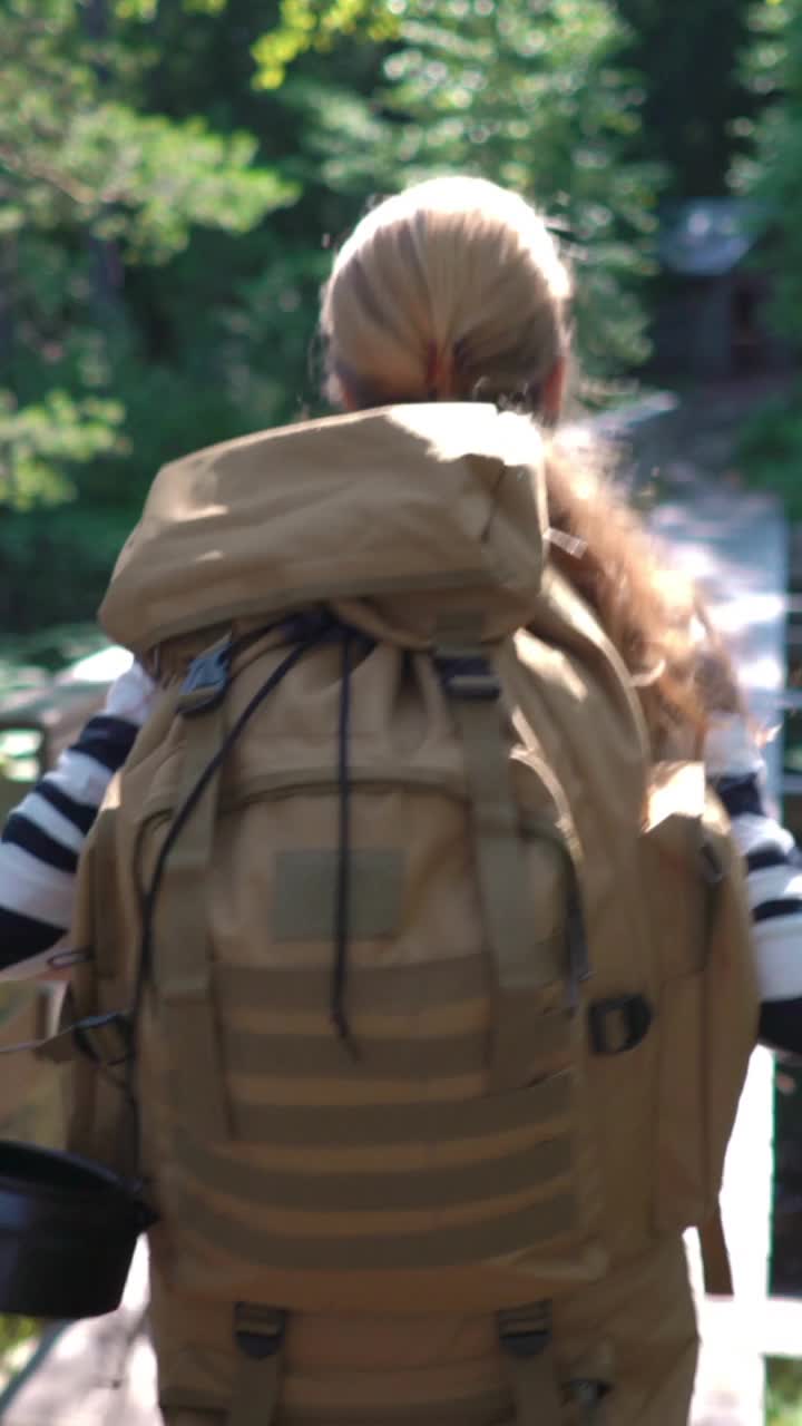 一个背着大背包的年轻女子在森林小径上徒步旅行视频素材