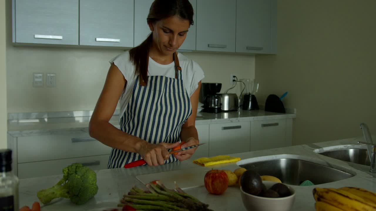 拉丁美洲年轻的素食妇女在家里准备午餐削胡萝卜视频素材