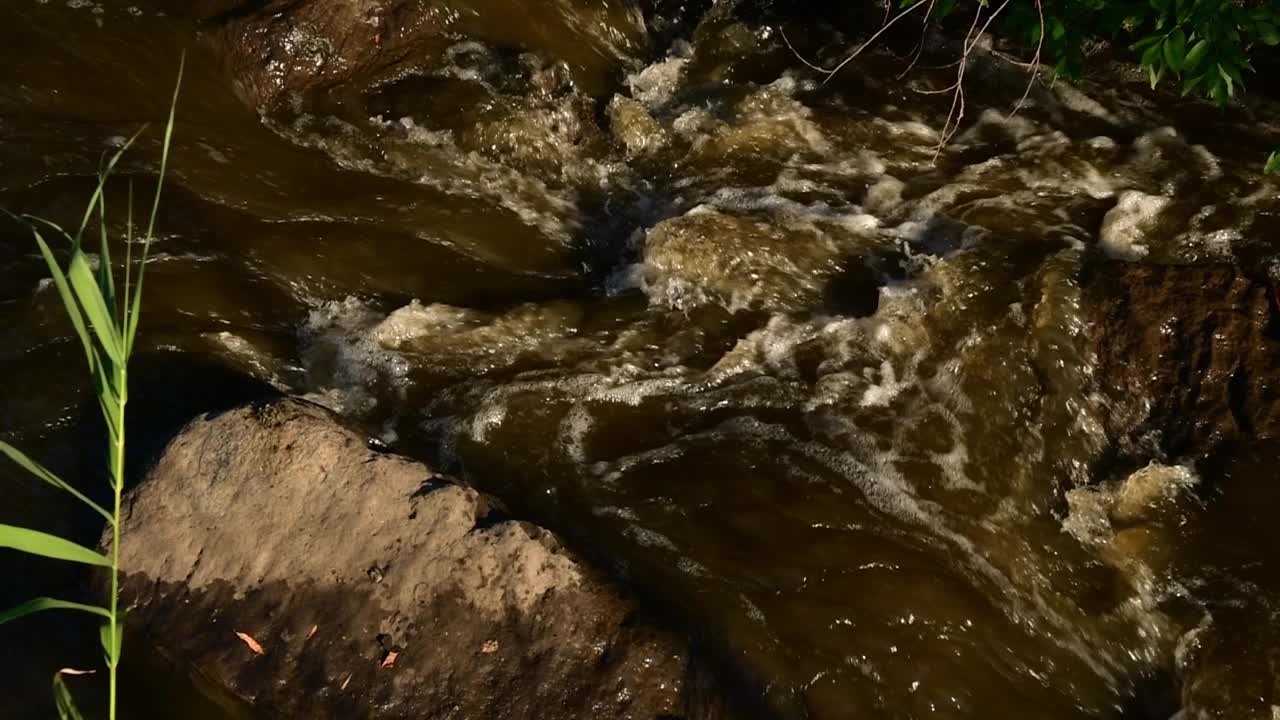 洪水灾害时，河里的脏水在花岗岩间流动视频素材