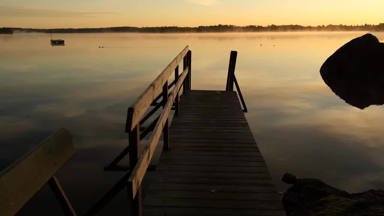 一个秋天的早晨，在一个安静的湖上的防波堤上视频素材