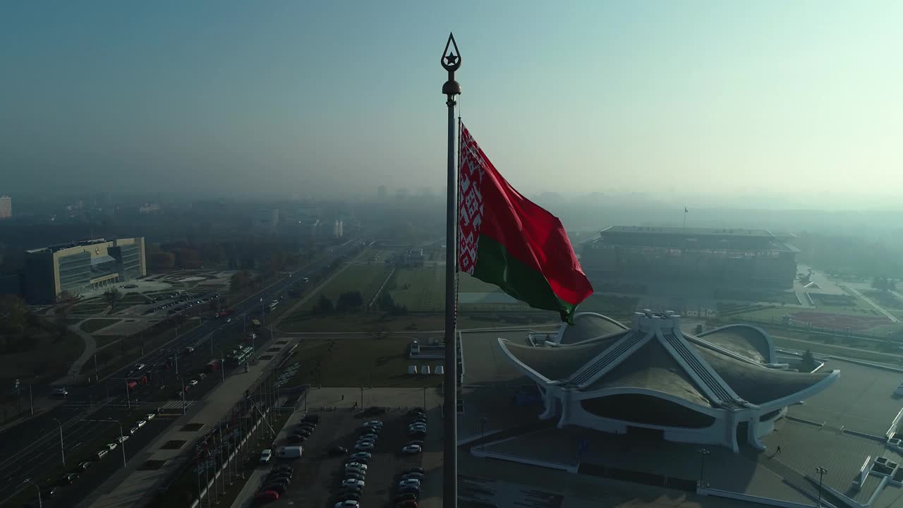 晴朗的早晨，白俄罗斯国旗飘扬在蔚蓝的天空和明斯克的城市景观上视频素材