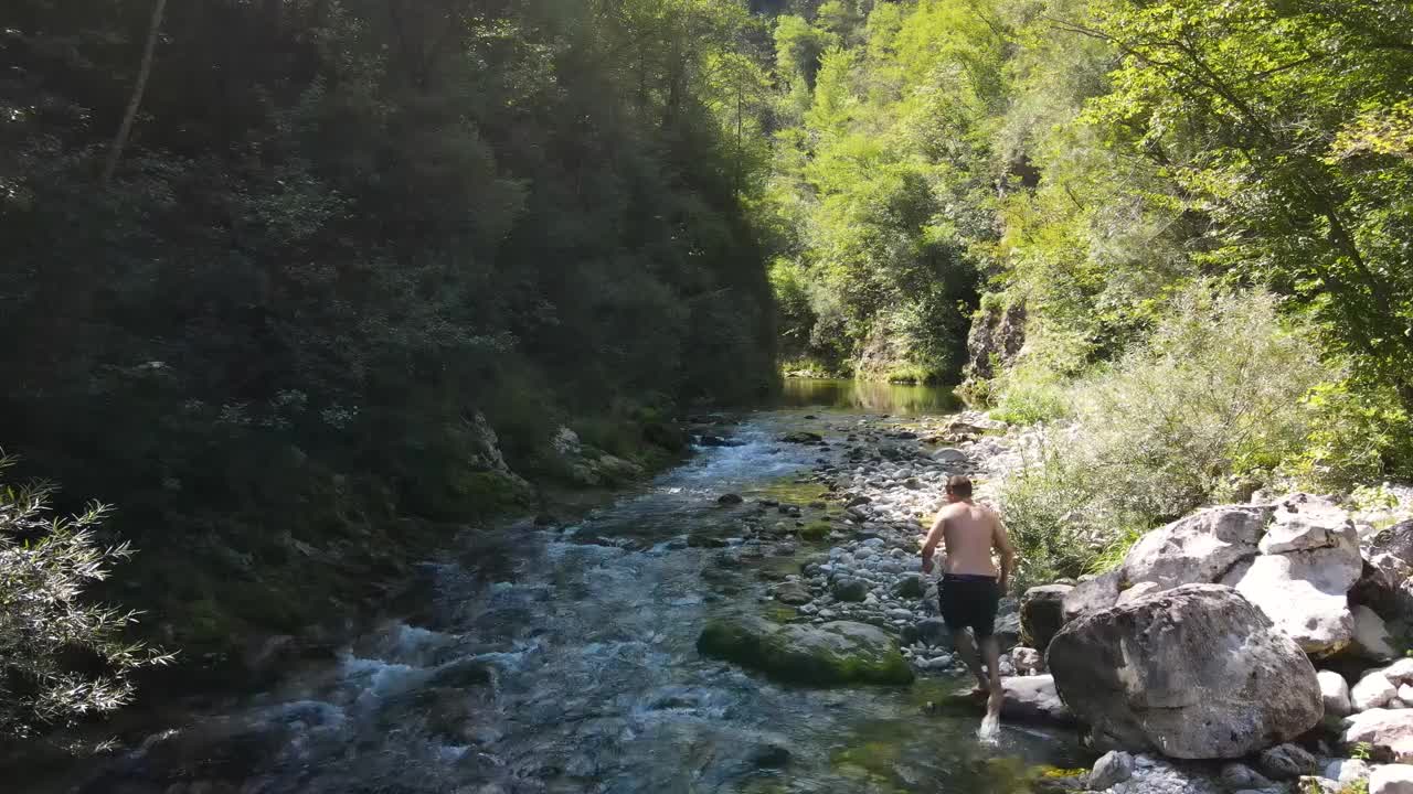 一个年轻人探索小河的跟踪镜头视频素材