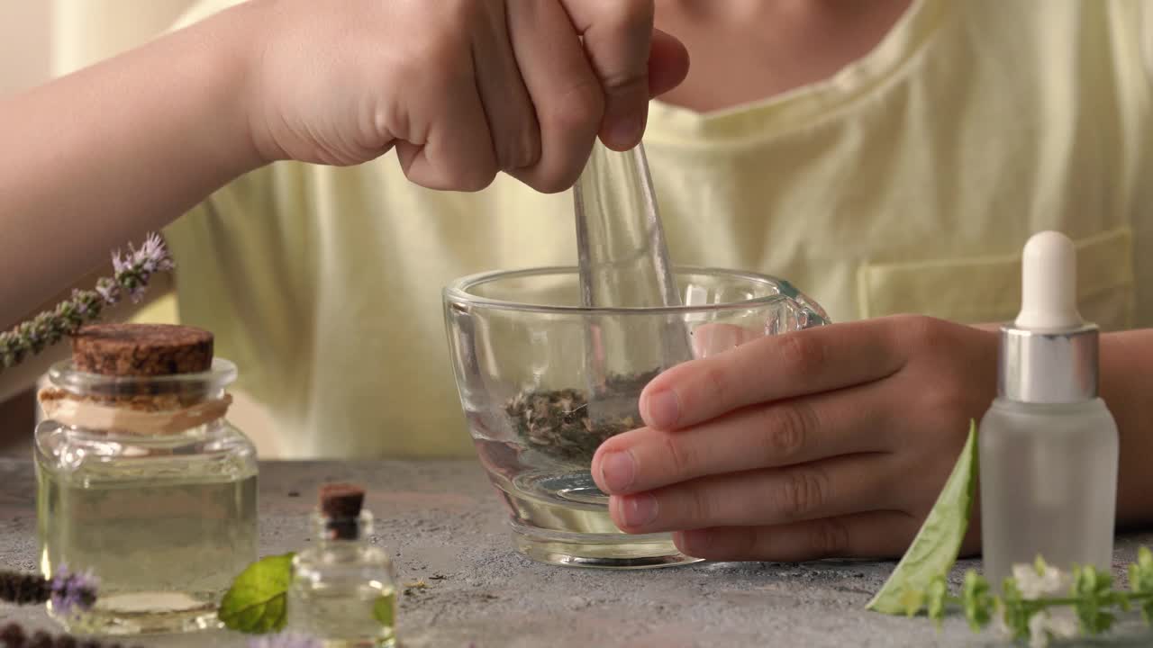 孩子在研钵里搅拌干香草，前景是香薰精油的瓶子视频素材