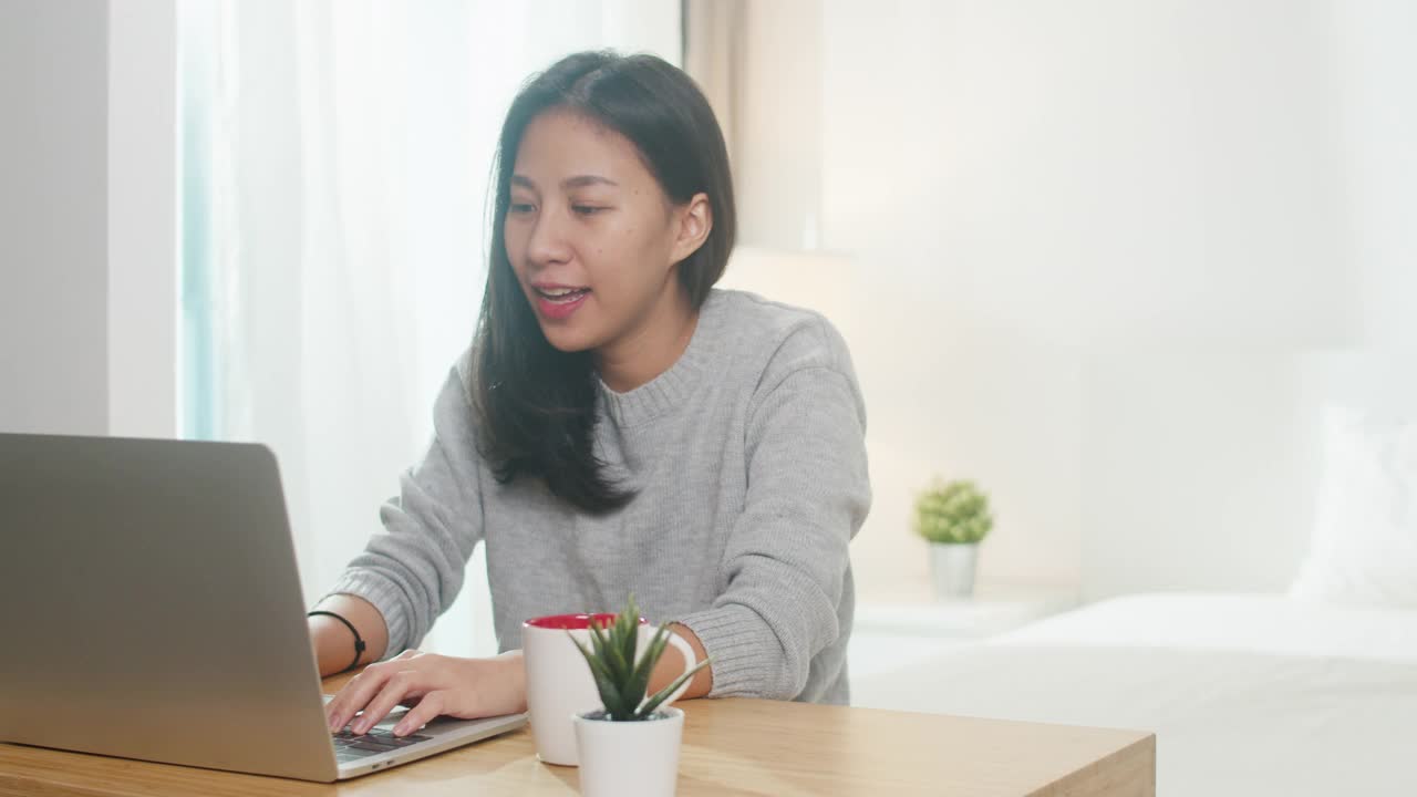 年轻的亚洲女商人使用笔记本电脑与同事在视频通话计划，同时在卧室智能工作。视频素材