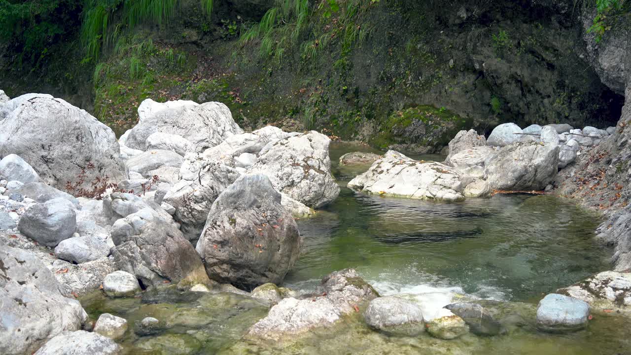 游客徒步旅行者正踏着山石走过河流。视频下载