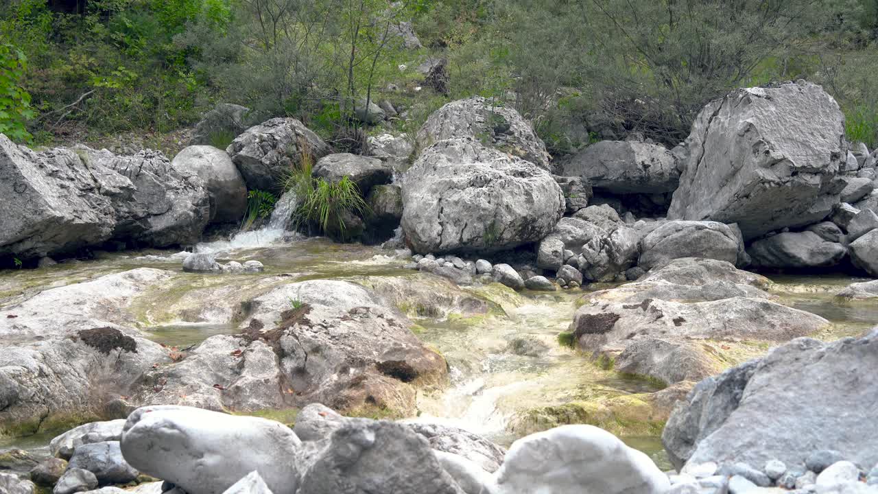 游客徒步旅行者在山河边的岩石边洗脸。视频下载