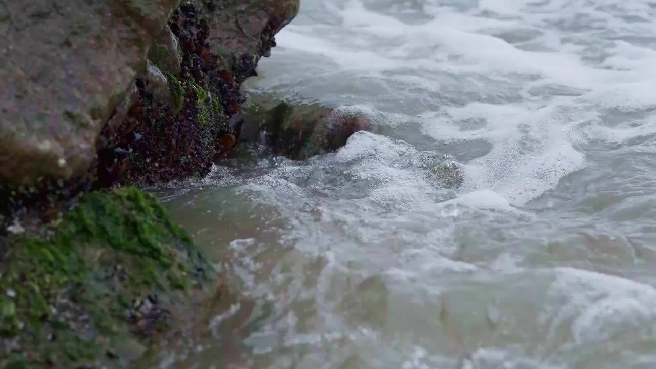 海浪的特写，泡沫冲上岸，撞击岩石视频素材