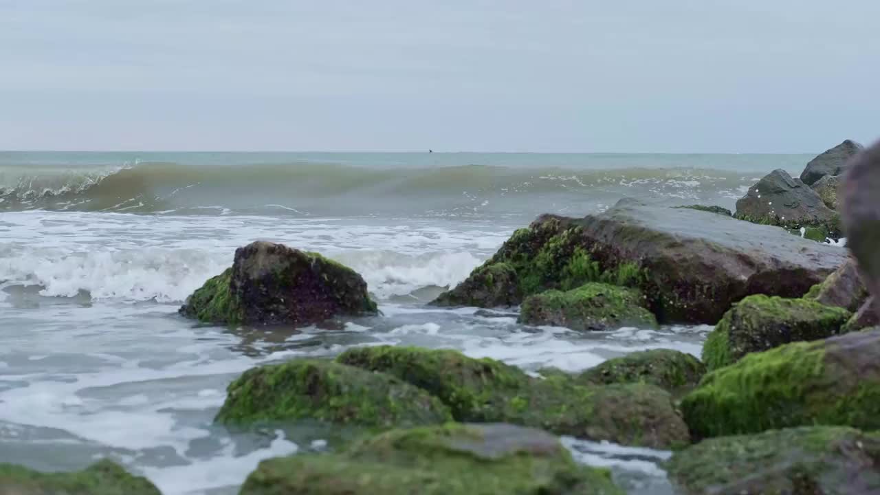 多云天气下的海景，海浪撞击着巨石视频素材