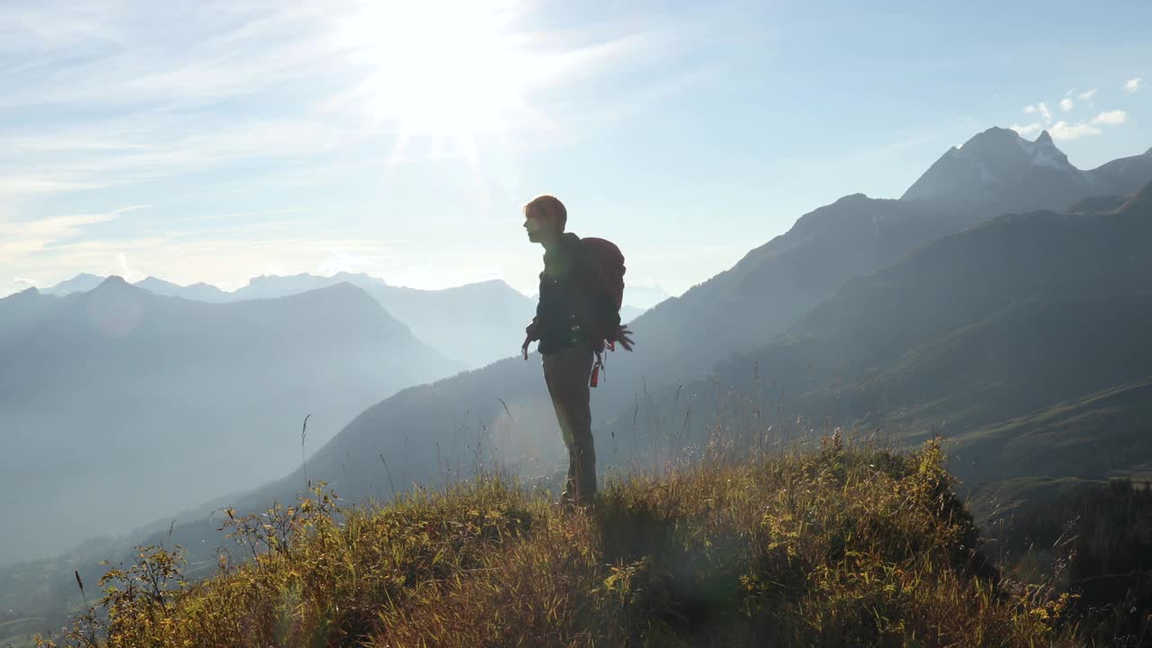 男性徒步旅行者在长满草的山顶上散步视频素材