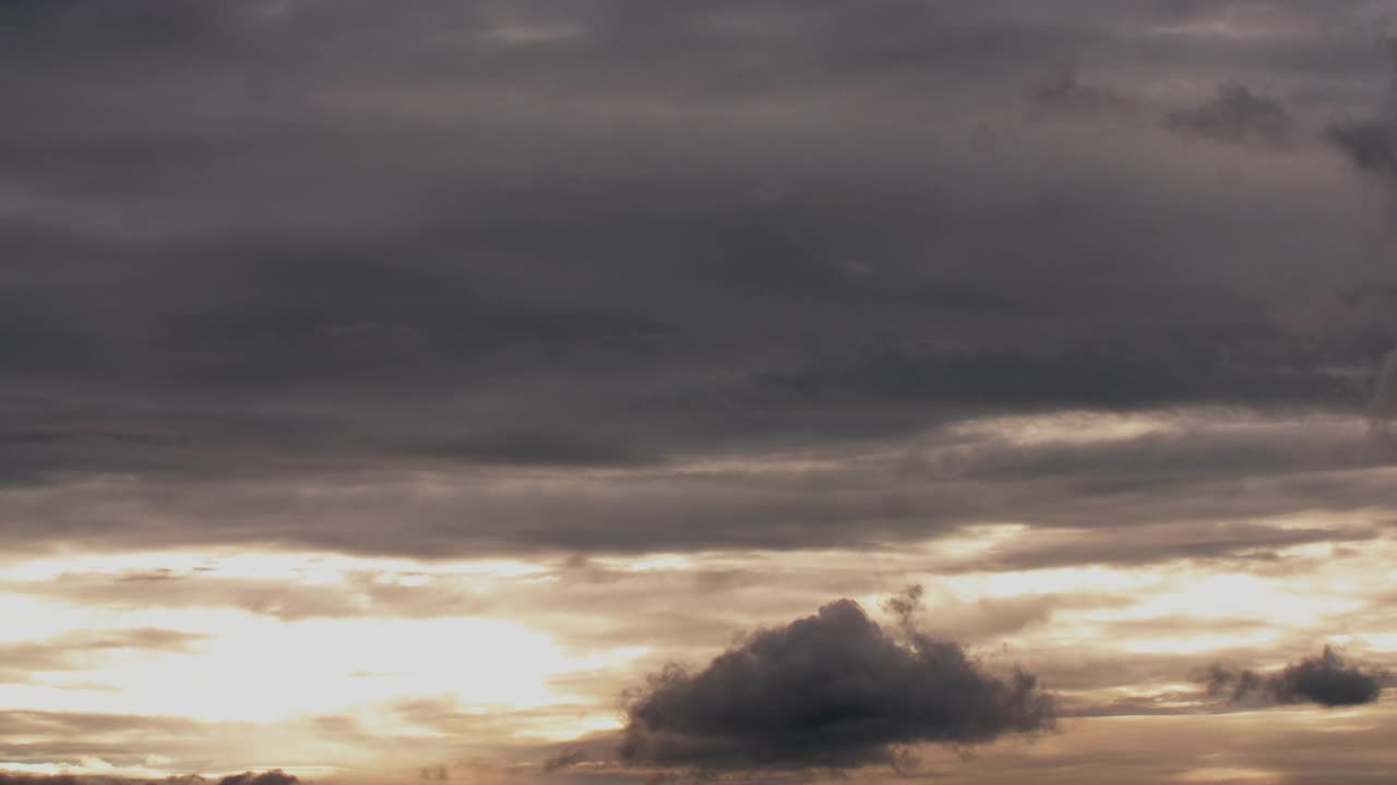 太阳照耀着阴沉沉的天空。天空中有灰色和白色的暴风云。视频素材