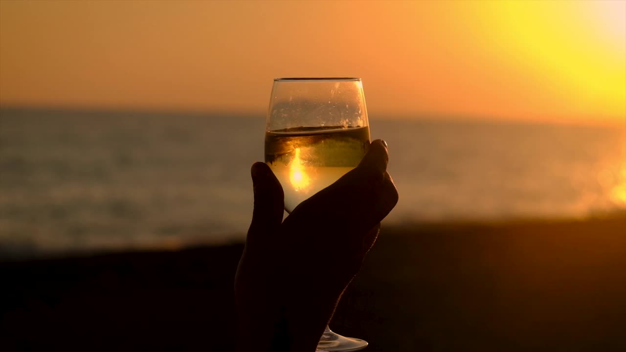 在海边日落时喝一杯酒。有选择性的重点。饮料。视频素材