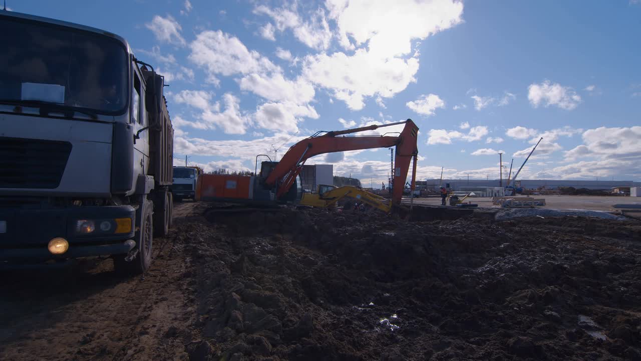 在建筑工地挖掘时，挖掘机将泥土装在卡车上视频素材