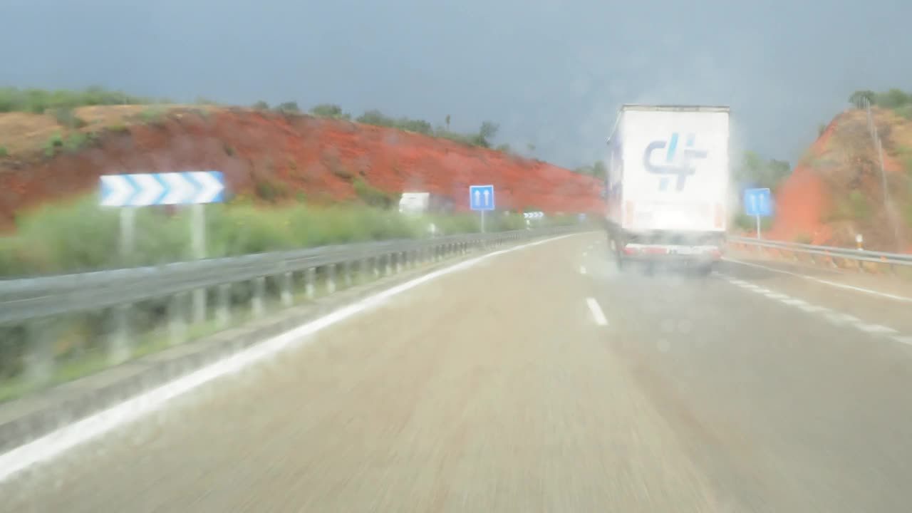 汽车视角驾驶。一辆汽车行驶在下雨的公路上，与一辆卡车擦肩而过。视频素材