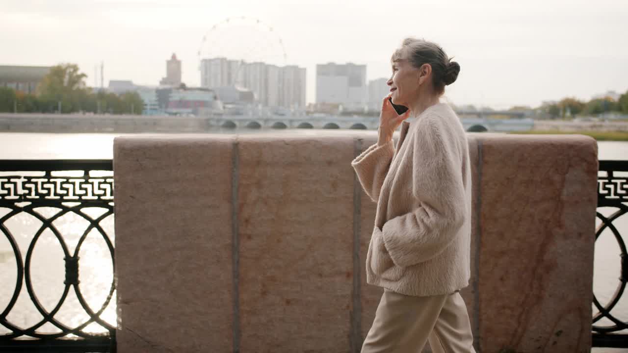 夏日里走在城市过桥上的大妈边走边聊手机视频素材