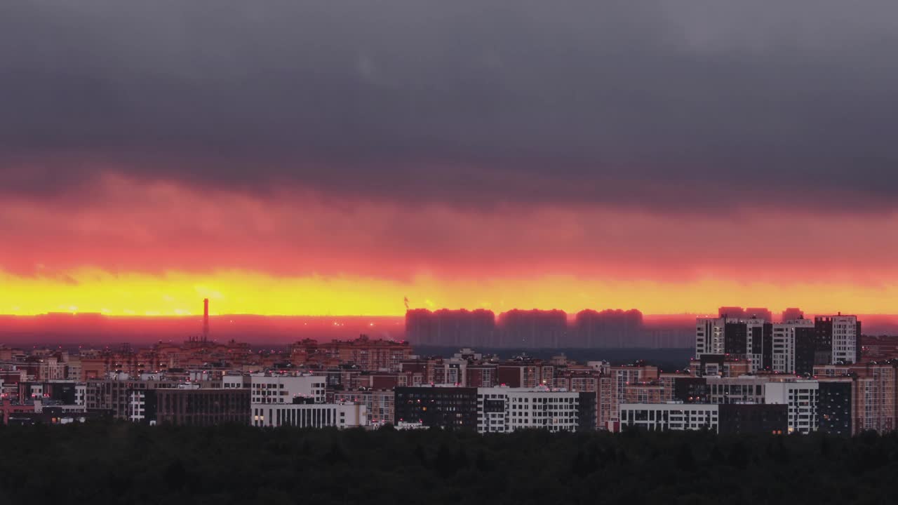 火红的太阳在城市建筑的轮廓后面，时间流逝。夏日的夕阳在天空中阴霾着夜屋，时光流逝视频素材