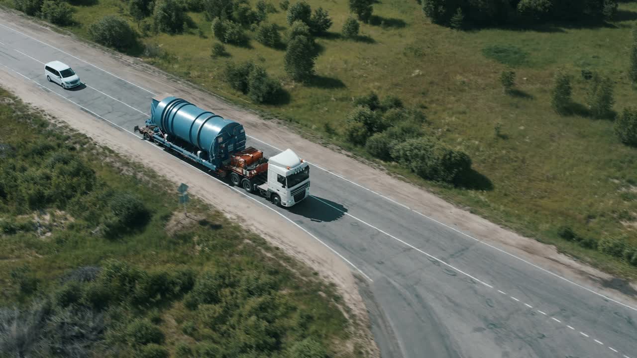 在穿越森林的公路上，一辆半卡车正开着车，载着货物视频素材