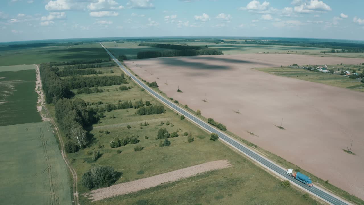 在穿越森林的公路上，一辆半卡车正开着车，载着货物视频素材