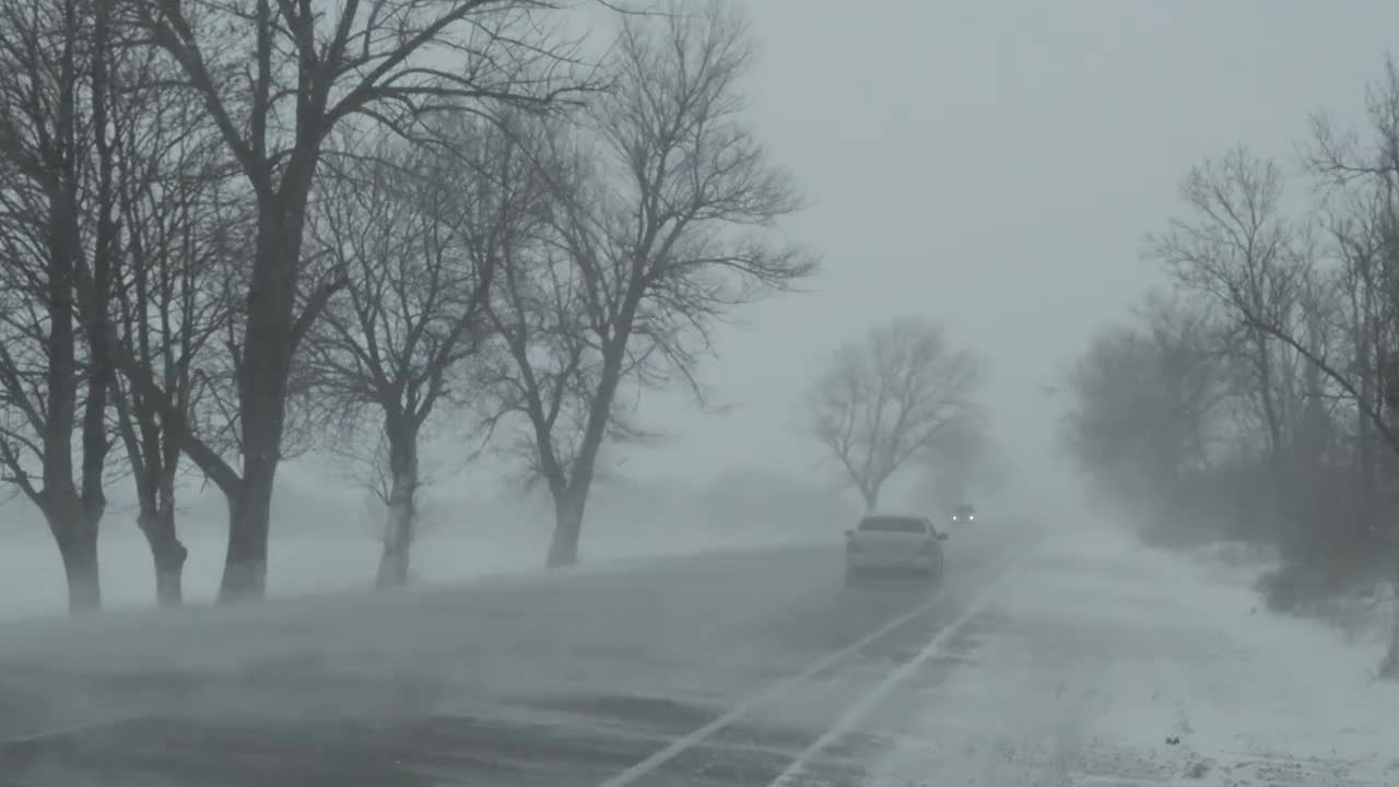 汽车在冬天的道路上暴风雪视频素材