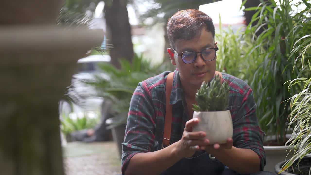 4K亚洲男人植物商店老板照顾植物和花卉在温室花园。视频素材