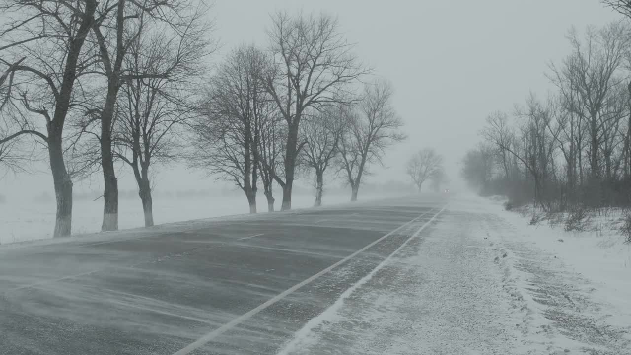 汽车在冬天的道路上暴风雪视频素材