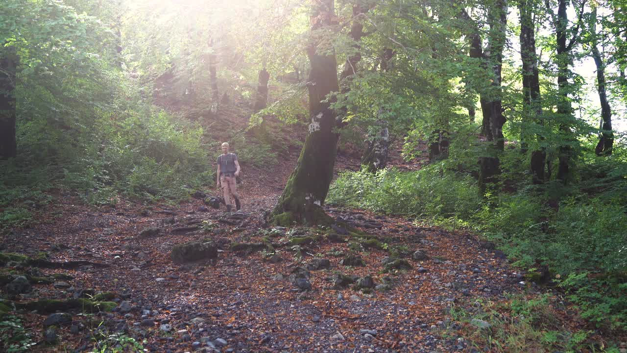 徒步旅行者背着背包走在山林里，徒步旅行的概念。视频素材