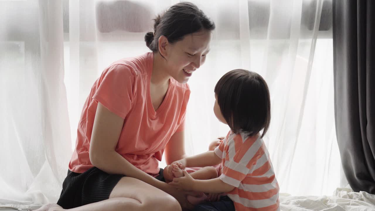 妈妈和妹妹在家里的卧室里照顾婴儿。视频素材