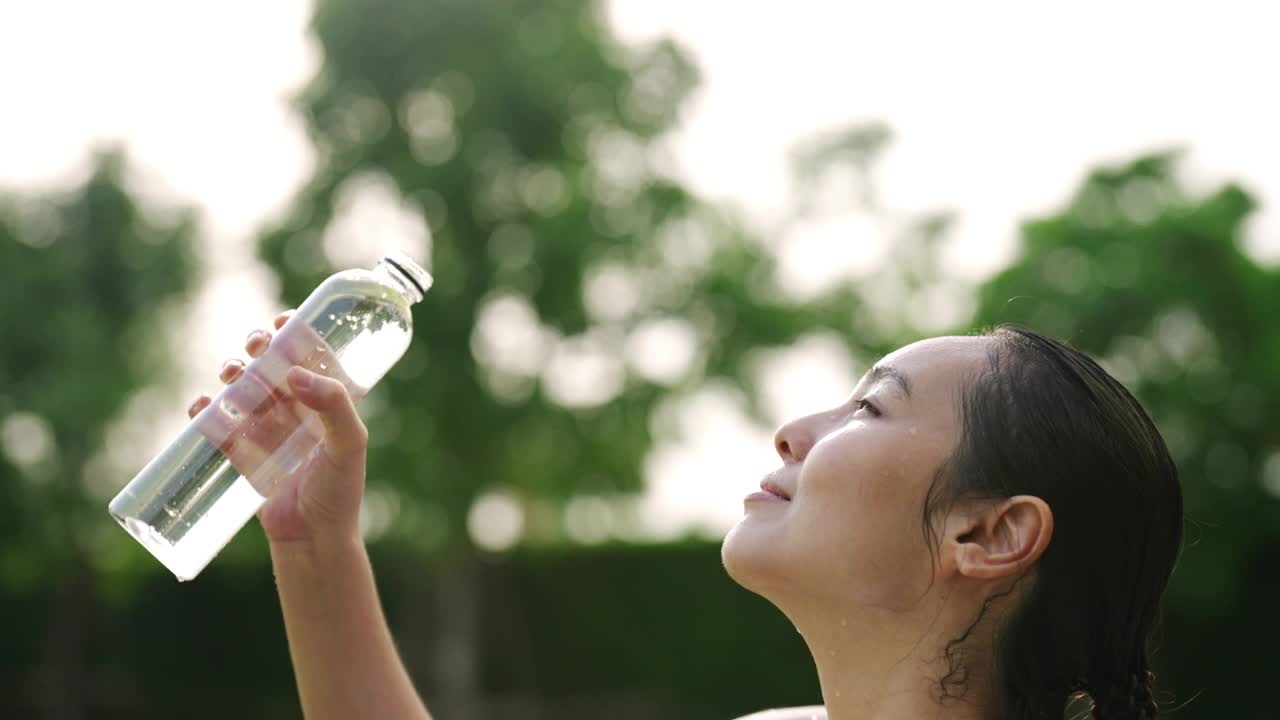 一名年轻女子在锻炼后往自己身上浇水视频素材