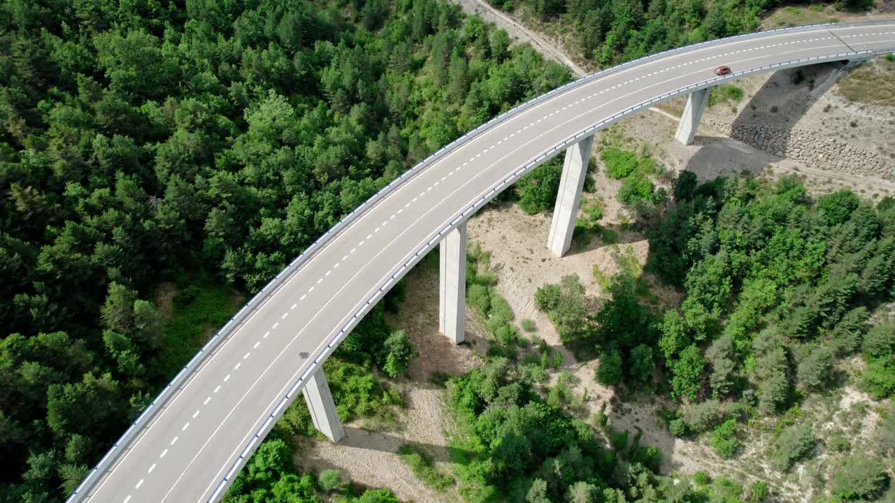 一座桥，一座山间的现代高架桥，一条三车道的柏油路。钢筋混凝土码头结构的桥梁连接两座小山，山上覆盖着森林。视频素材