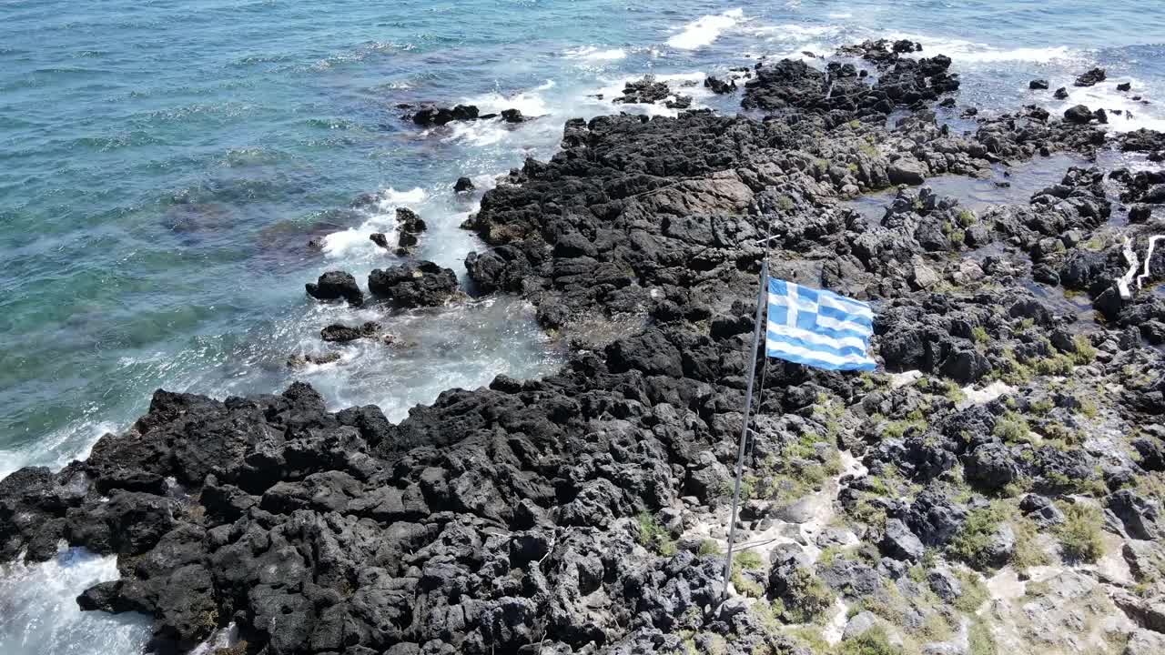 岩石海岸上飘扬的希腊国旗上的美丽景色。视频素材