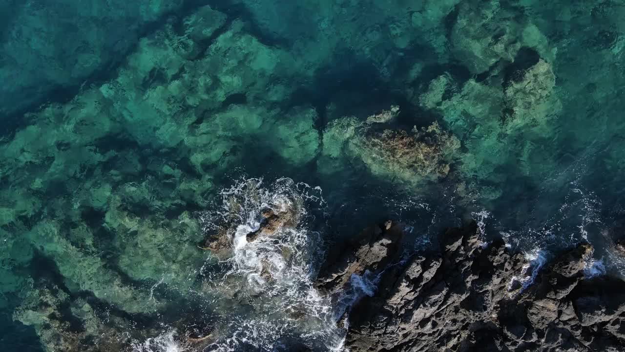 无人机在蓝绿色的海水，海浪，飞溅，泡沫和岩石上的视图。视频素材