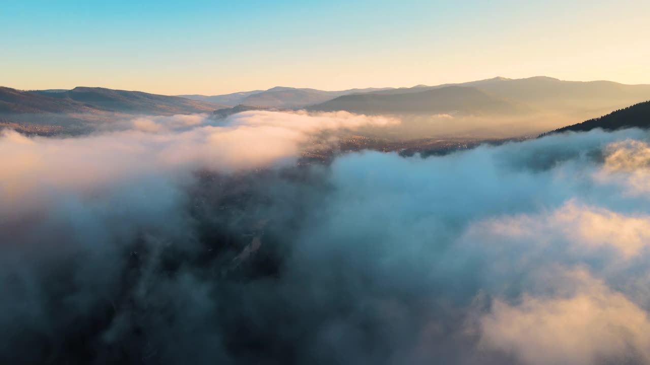 鸟瞰图的景观在雾蒙蒙的快速移动的云覆盖山在日落。视频素材