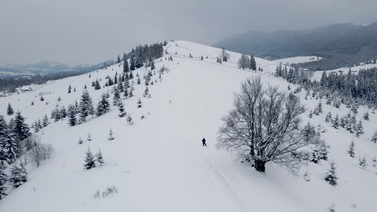 空中冬季景观与小乡村房屋之间的雪覆盖森林在寒冷的山。视频素材