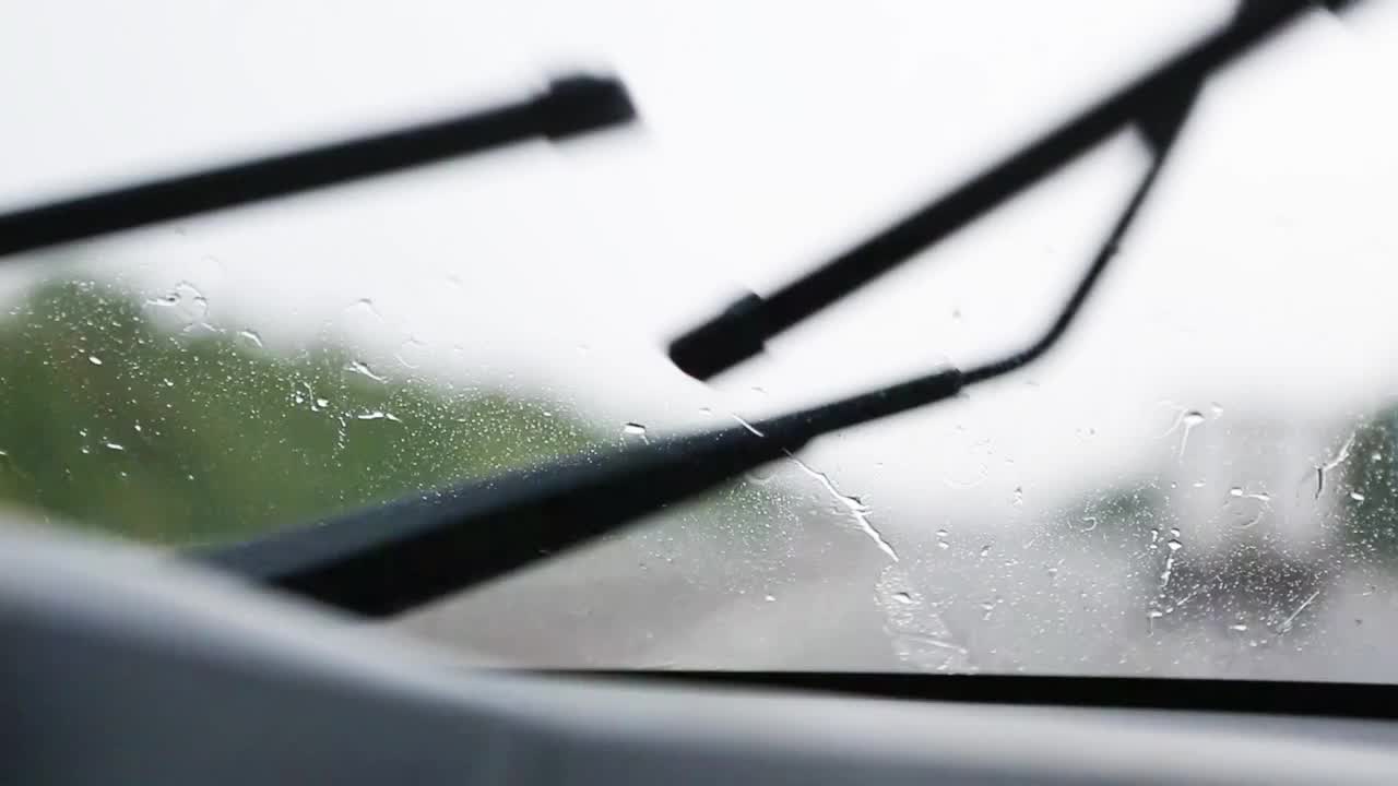 在能见度有限的情况下驾驶汽车:大雨，雨刷清洁挡风玻璃。高速公路上迎面而来的车辆开着前灯。恶劣天气条件下的道路安全。从车内看视频素材