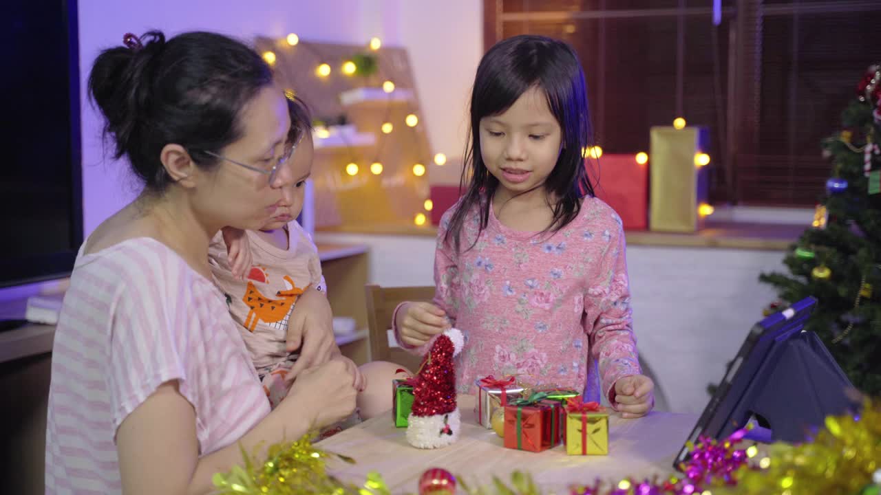 亚洲妇女与两个女孩使用笔记本电脑视频通话在庆祝圣诞节假期派对视频素材