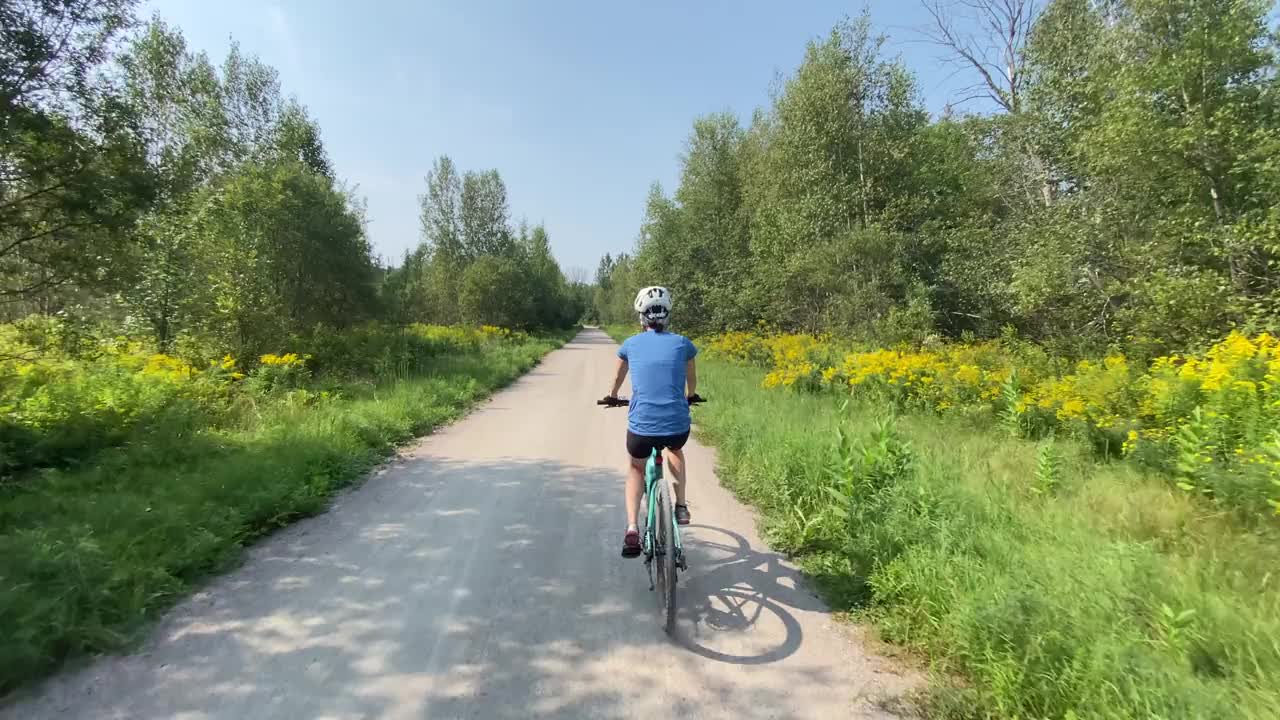 在森林中的自行车道上骑自行车的女人，魁北克，加拿大。视频素材