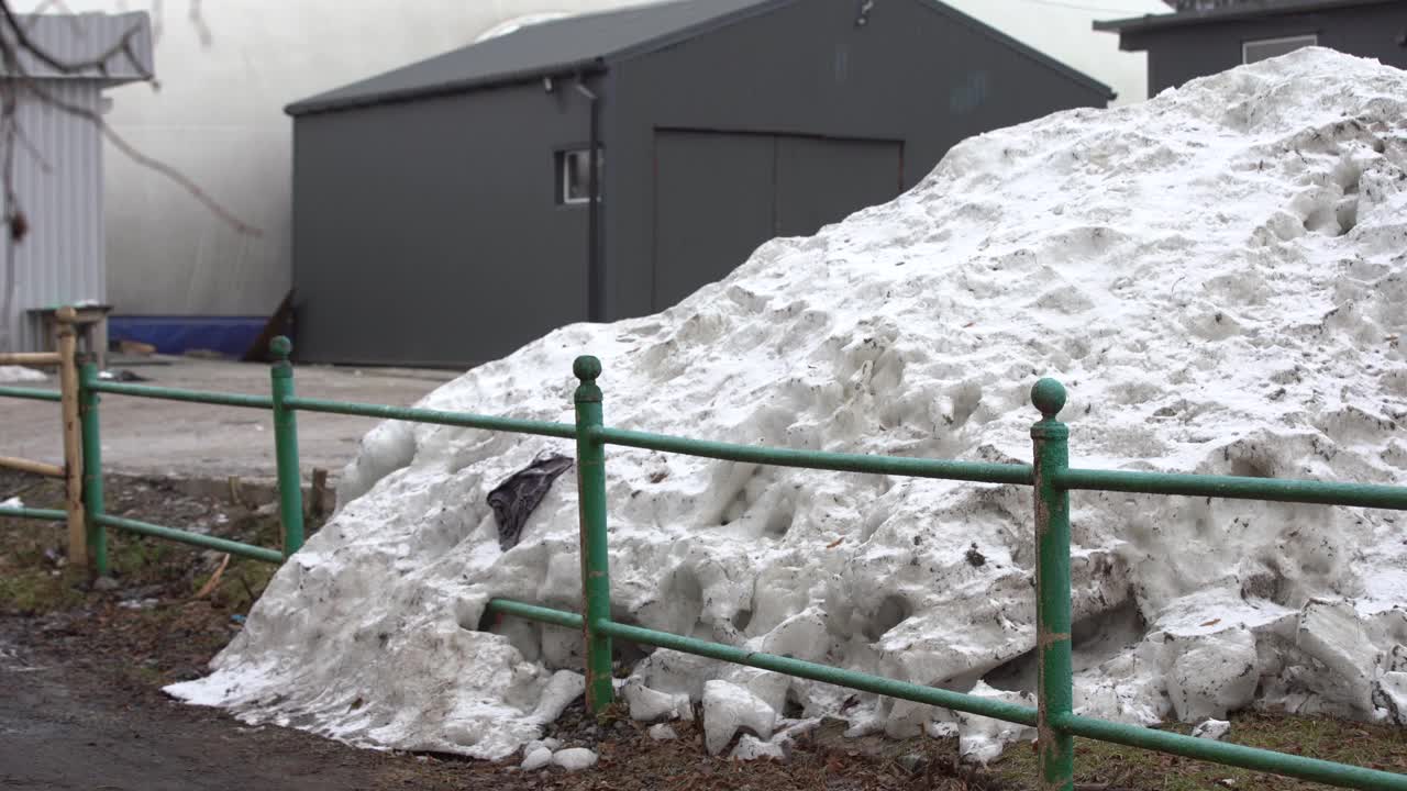 在冬季异常降雪后，城市里堆积如山的脏雪是由道路附近的除雪设备收集的视频素材