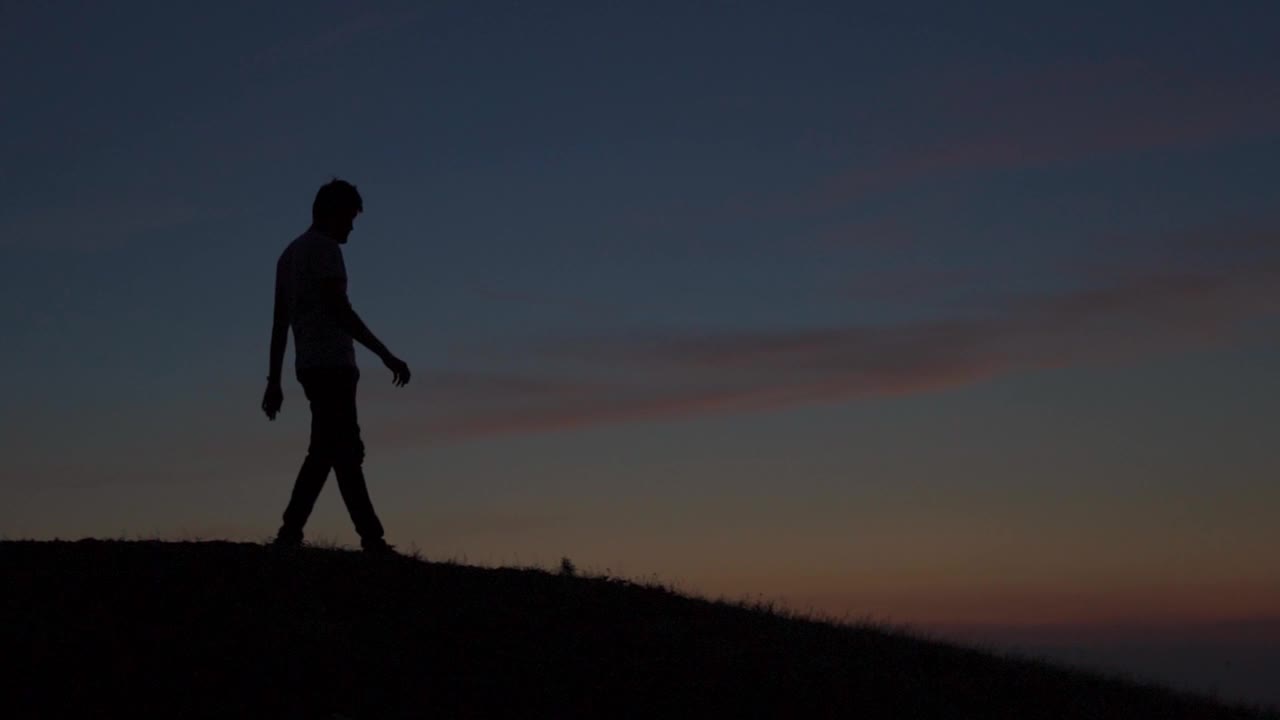 一个印度人在夕阳下下山的剪影。日落时，徒步者从山顶下来，徒步者到达山顶后返回。旅游的背景。视频素材