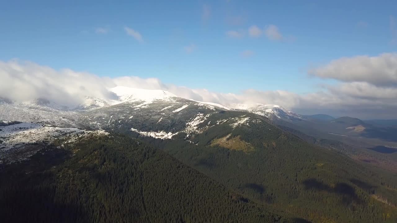 鸟瞰覆盖着绿色云杉森林和高雪峰的雄伟山脉。视频素材