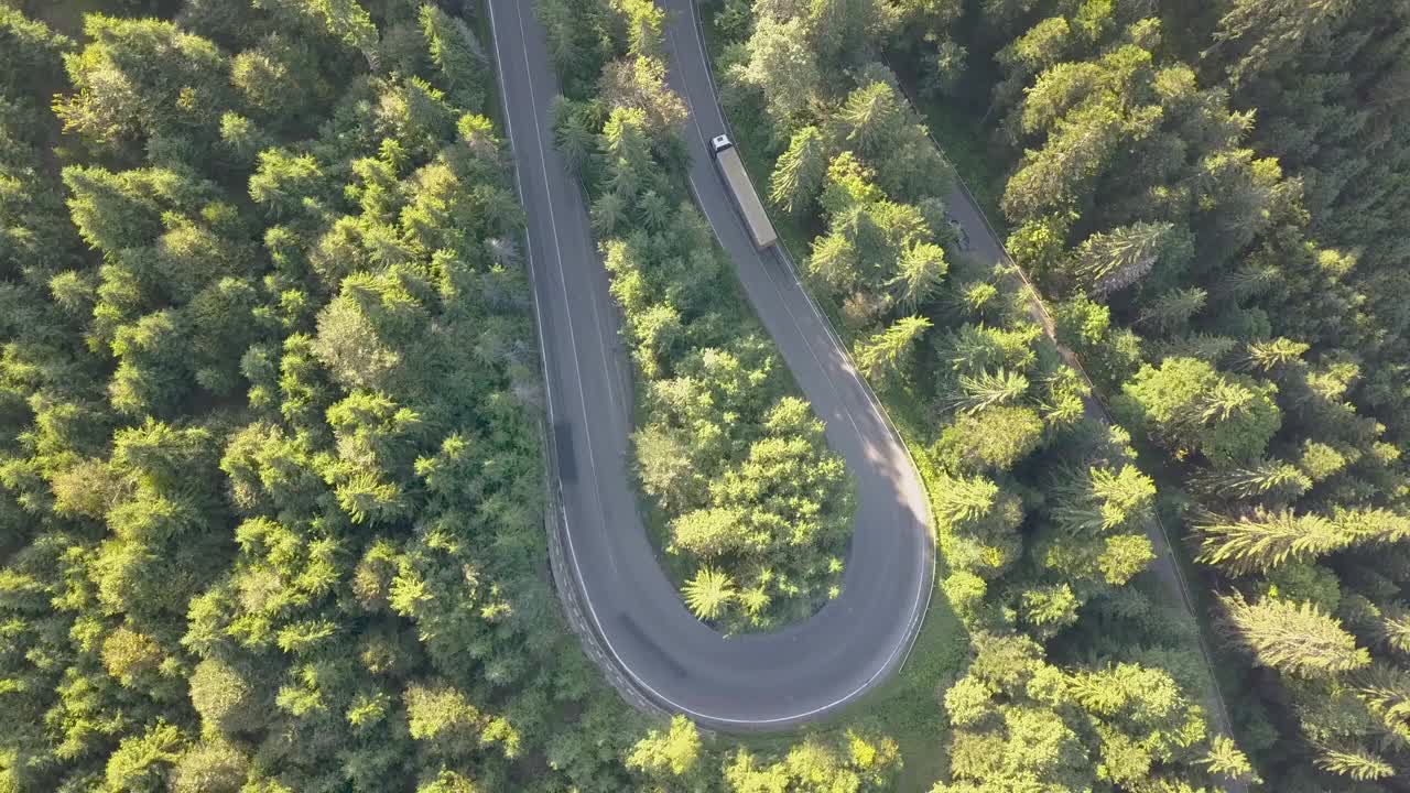 鸟瞰图的蜿蜒的道路与割草汽车和卡车在高山口，槽茂密的树林。视频素材