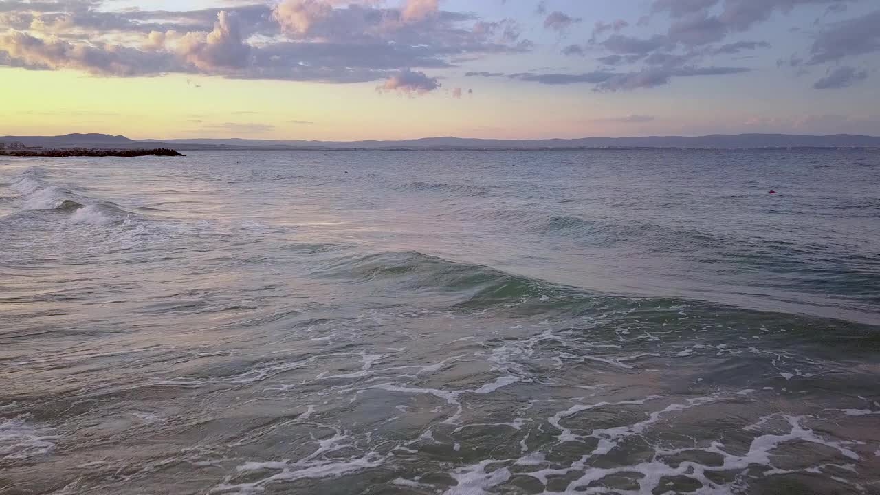 鸟瞰图的海面与蓝色的海浪在日落的天空下。视频素材