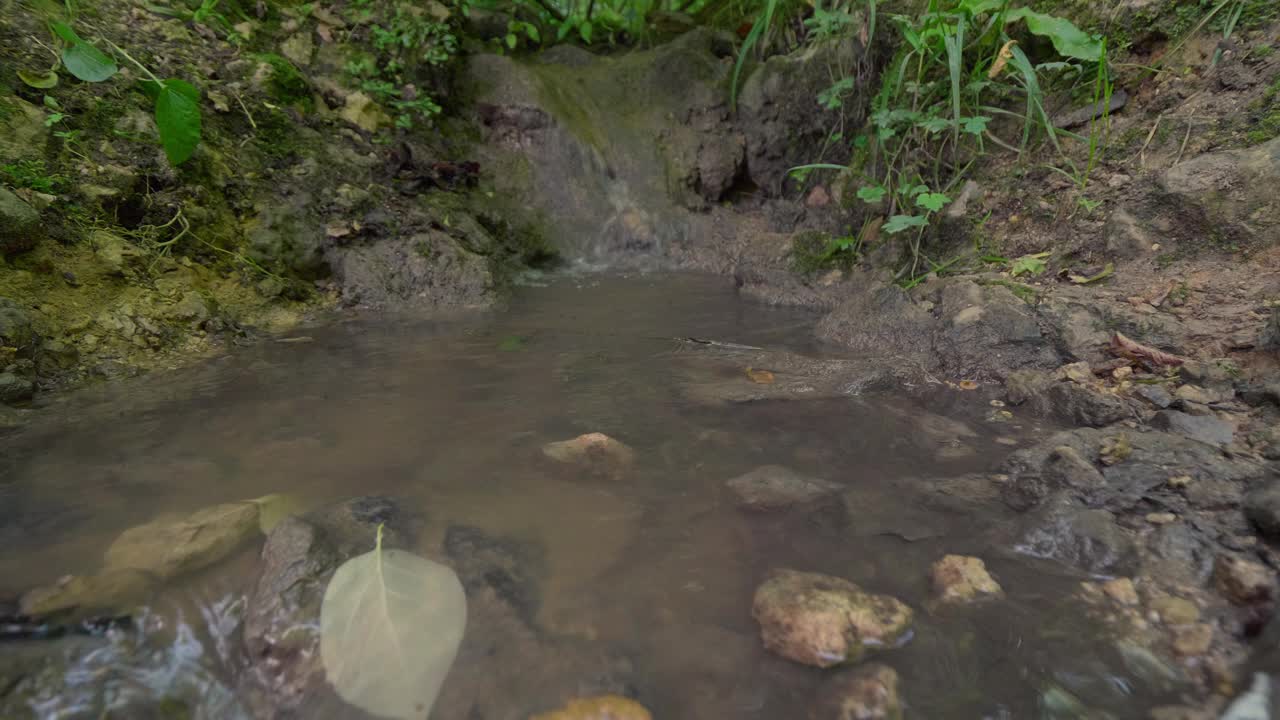 泉水在充满岩石和碎石的粘土小溪上流动视频素材