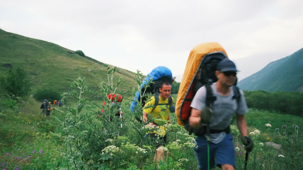 一群徒步旅行者背着巨大的背包在山谷中行走。视频素材